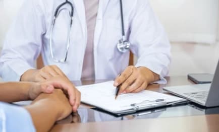 A doctor writing notes on a clipboard during a consultation